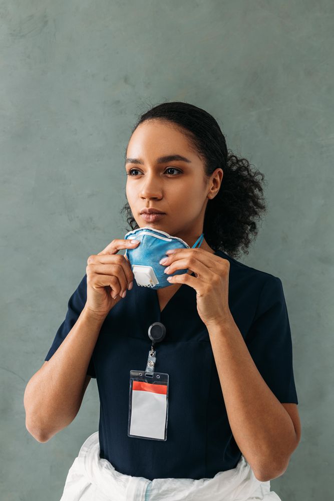 Confident female medical professional putting on a protective mask