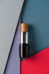 Concealer stick on modern background with geometric shapes.