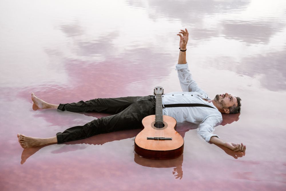 Man resting in water with guitar at seaside