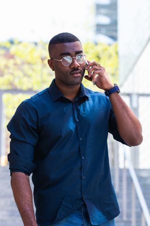 Serious Black male talking on cellphone in street