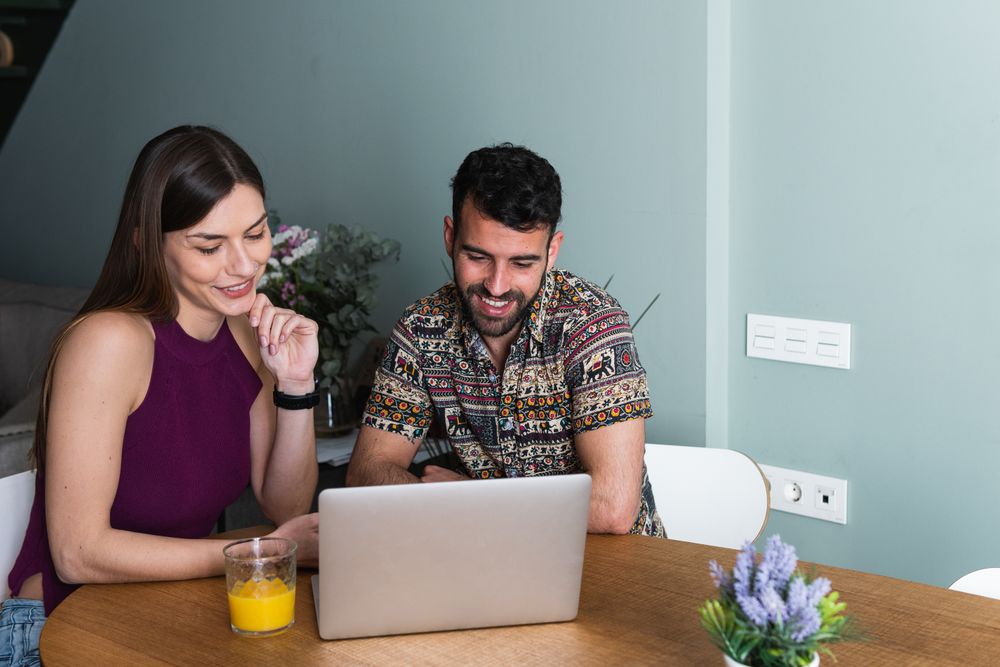 Cheerful couple using laptop in living room