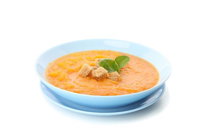 Bowl of pumpkin soup with croutons and spoon