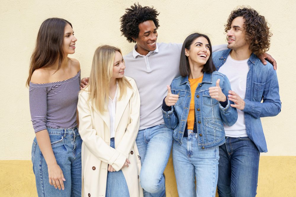 Happy people posing for portrait leaning against a yellow wall