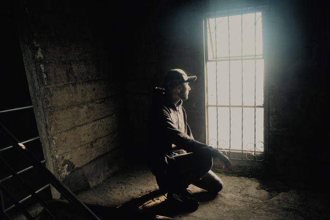 Young man sitting near window in abandoned building