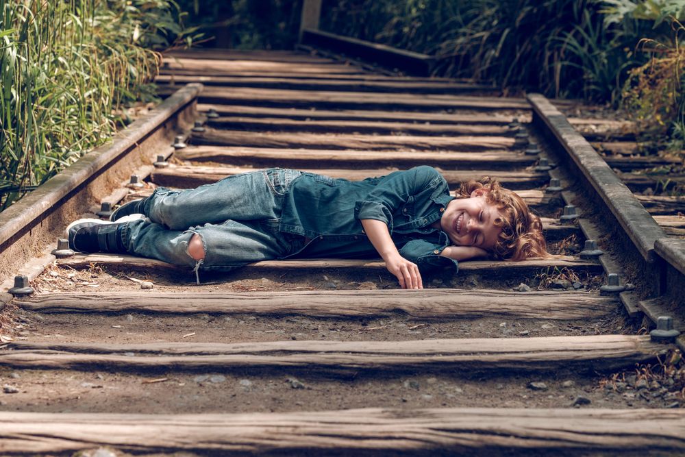 Cheerful boy lying on railroad