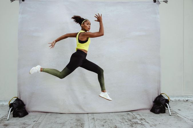 Young woman athlete in sportswear with fit body jumping high in midair