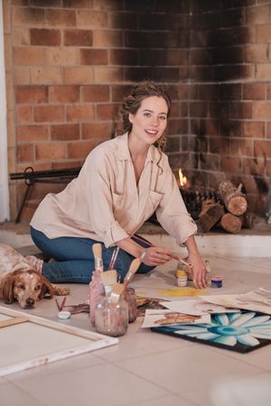 Woman drawing with dog and looking at camera