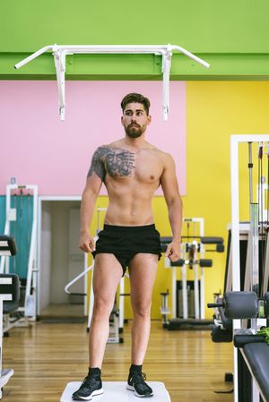 Front of man standing under pull up bar in colorful gym