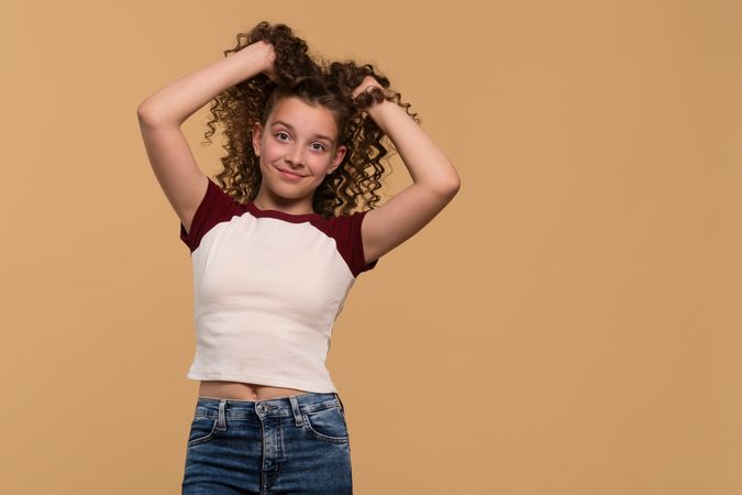 Young girl playfully holding hair up, smiling cheerfully