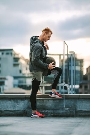 Fitness man standing on rooftop holding a medicine ball