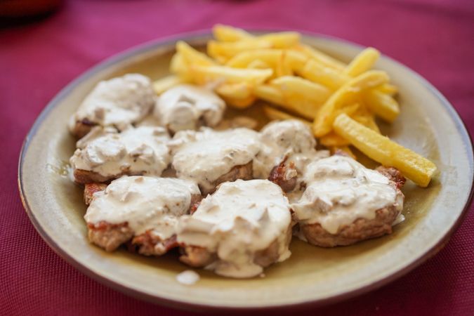 Plate with fries with meat in sauce in restaurant