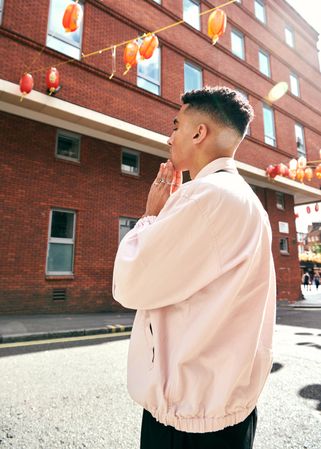 Stylish young man with hands to chin posing in Chinatown