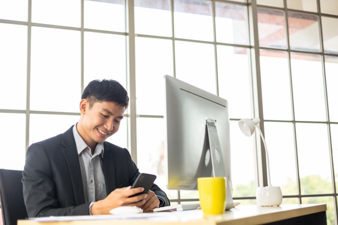 Smiling man in is office checking his phone