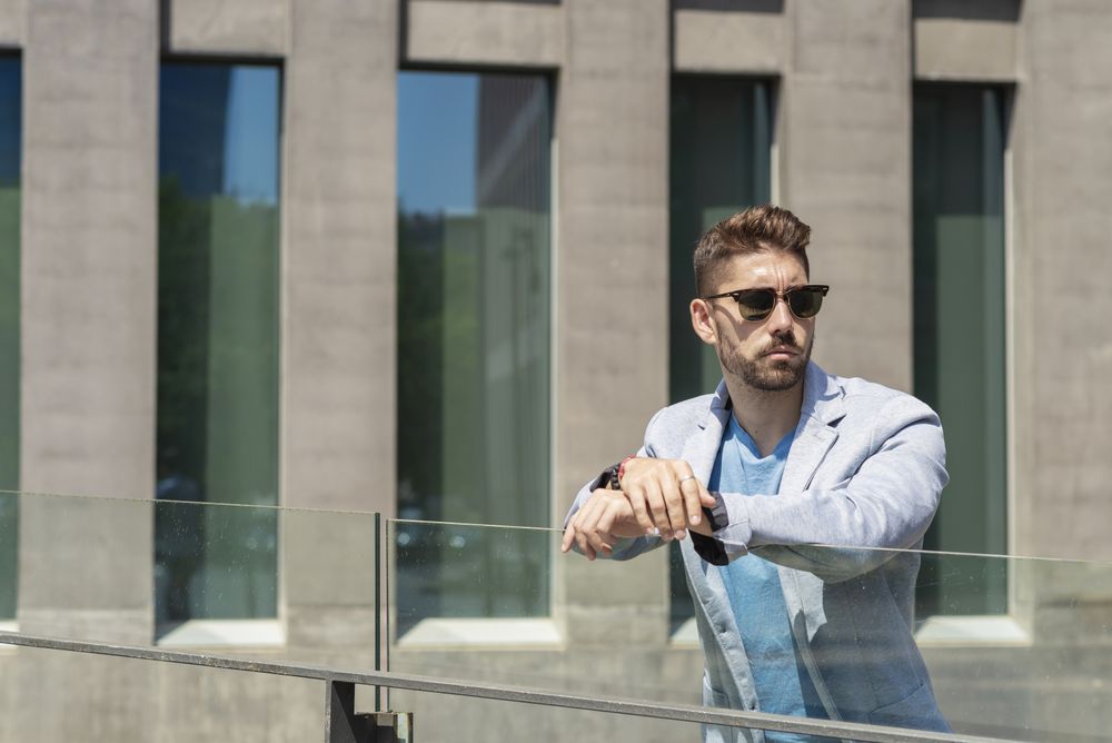 Serious bearded man leaning on a fence while looking away in the city