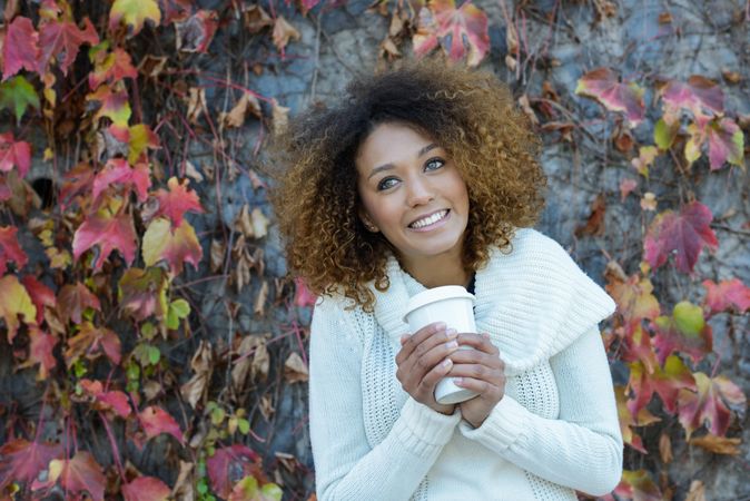 Smiling Black woman drinking coffee in park