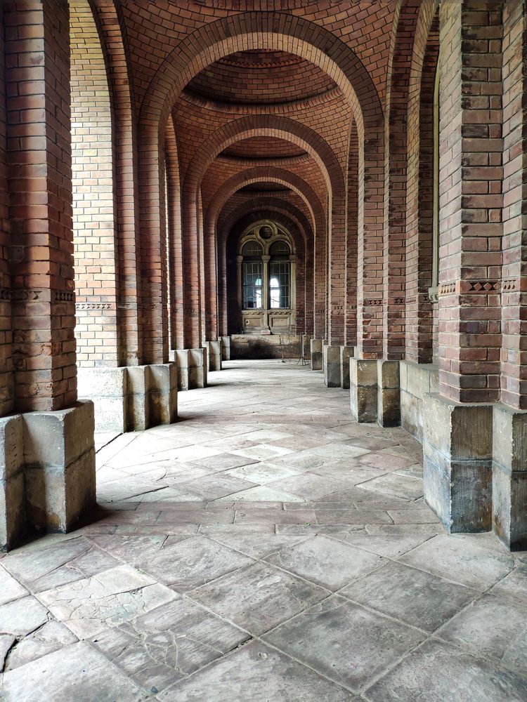 Old brick arch with tiles on the floor and closed doors