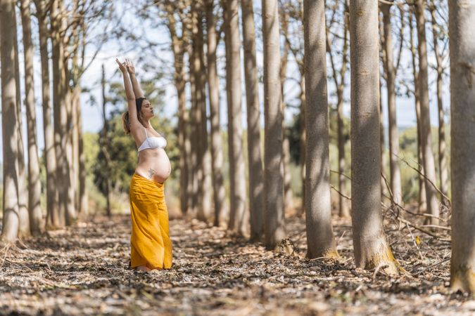 Concentrated adult expectant mother practicing yoga in park