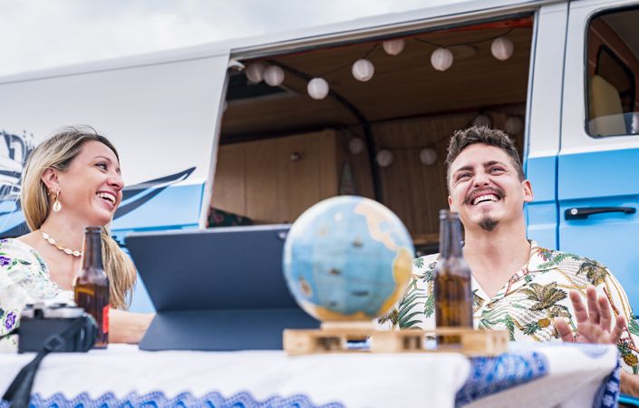 Smiling friends clinking bottles of beer celebrating vacation