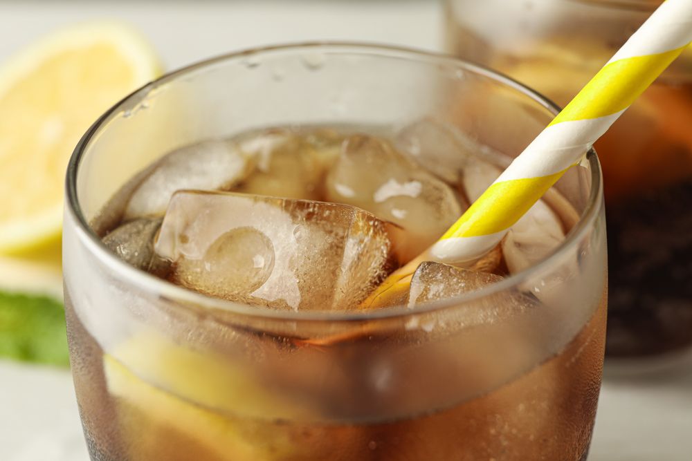 Glasses with cold cola and citrus on cement background, closeup