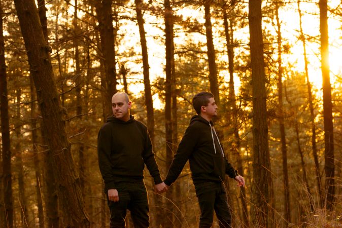 Men holding hands and walking in forest
