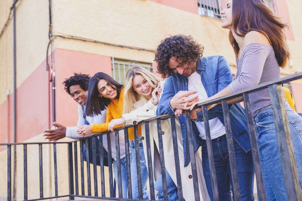 Portrait of happy male and female friends talking on street outside