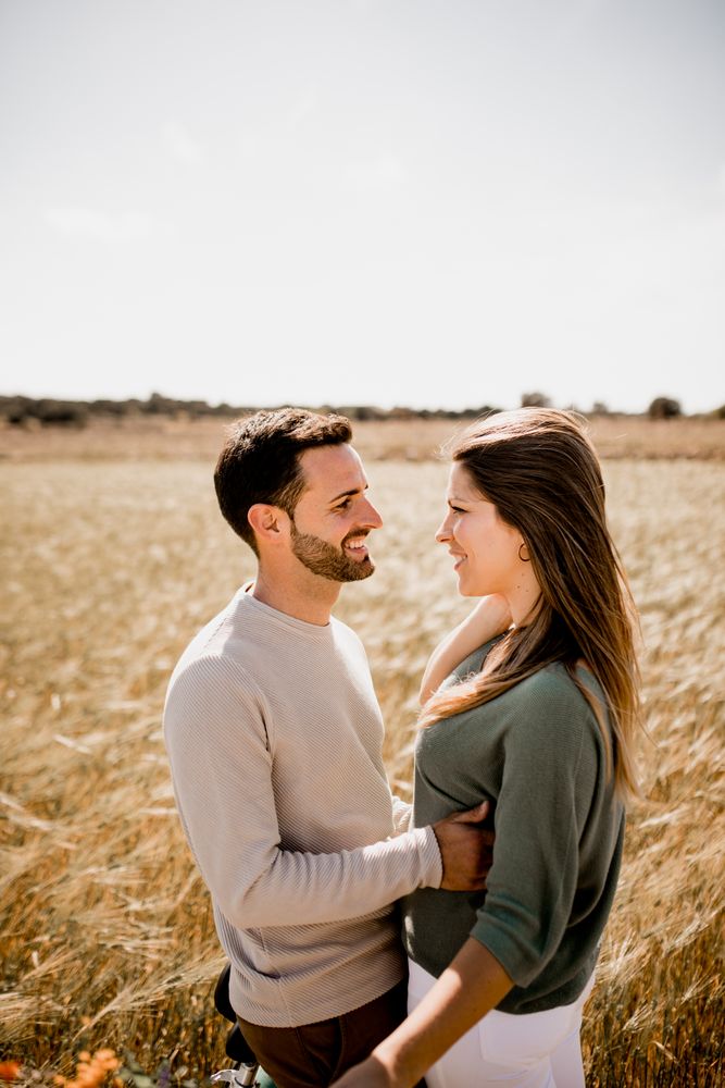 Sincere lovers posing by bicycle on rye field