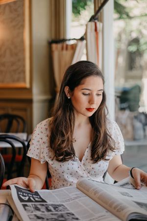 Woman reading a newspaper in a bright cafe