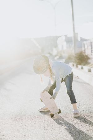 Stylish girl with skateboard on street
