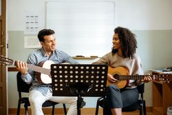 Man and woman playing guitar in studio