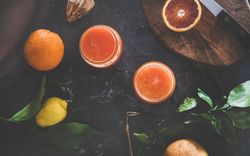 Two glasses of freshly squeezed blood orange juice, with squeezer, and fruit, top view