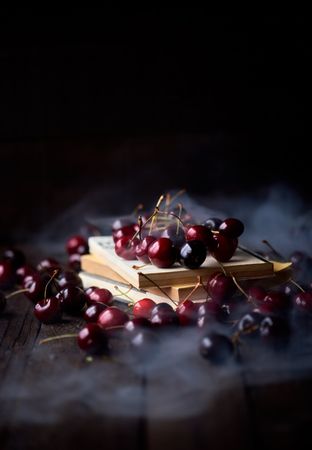 Cherries on top of old books with a layer of thick smoke