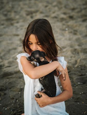 Girl with little dog on sandy beach