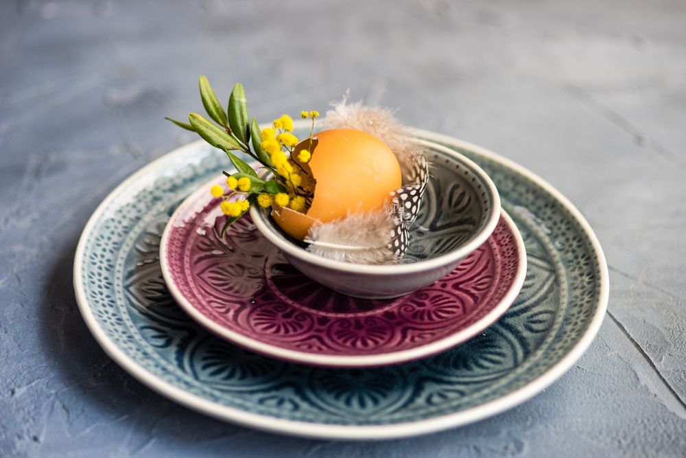 Easter table setting with egg and foliage on patterned plate