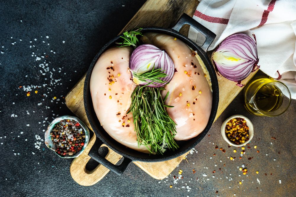 Top view of raw chicken in pan ready to cook on cutting board with copy space