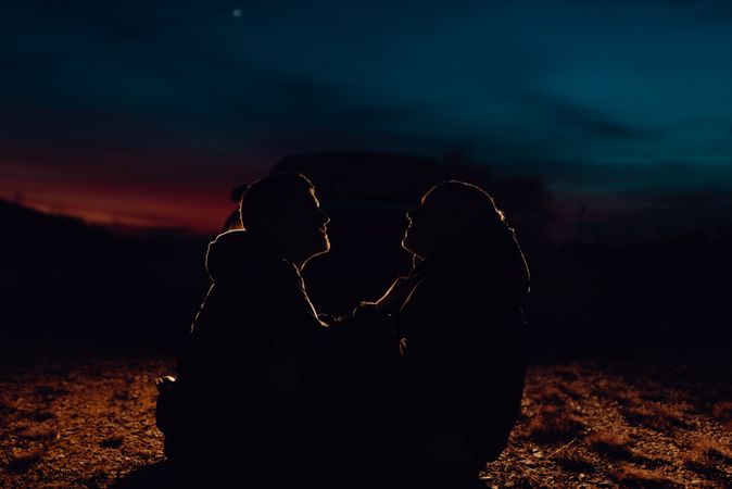 Men hugging and sitting on ground on field at night