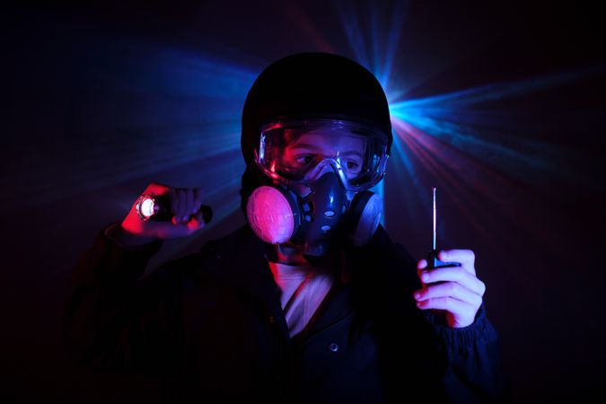 Boy with walkie talkie and in mask in dark studio