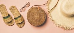 Sandals, glasses, bag, straw hat on pink background, wide composition