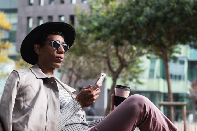 Stylish man with smartphone and coffee to go outdoors