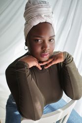 Confident Black female in headwrap with hands at chin