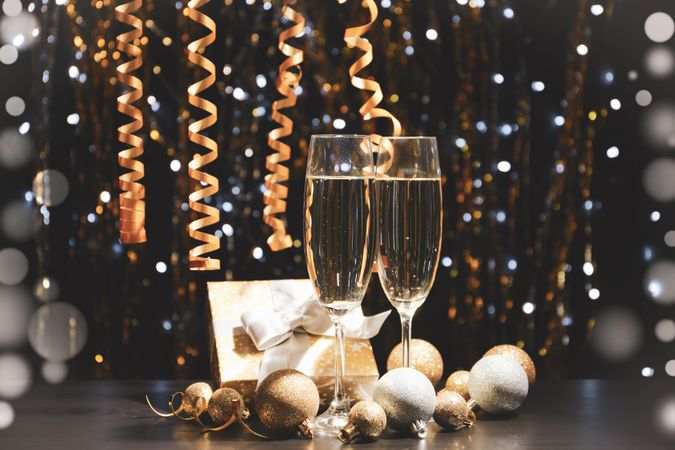 Christmas baubles and champagne glasses on blurred background, copy space