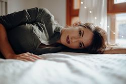 Woman lying on bed and looking at camera