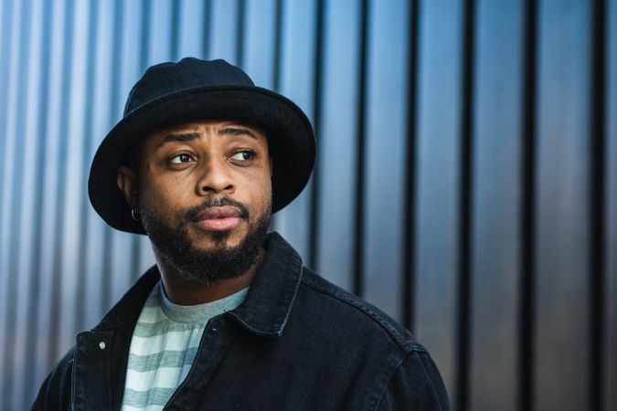 Smiling Black hipster man in hat looking away