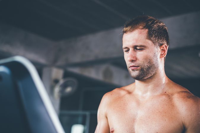 Man looking down at treadmill screen in gym