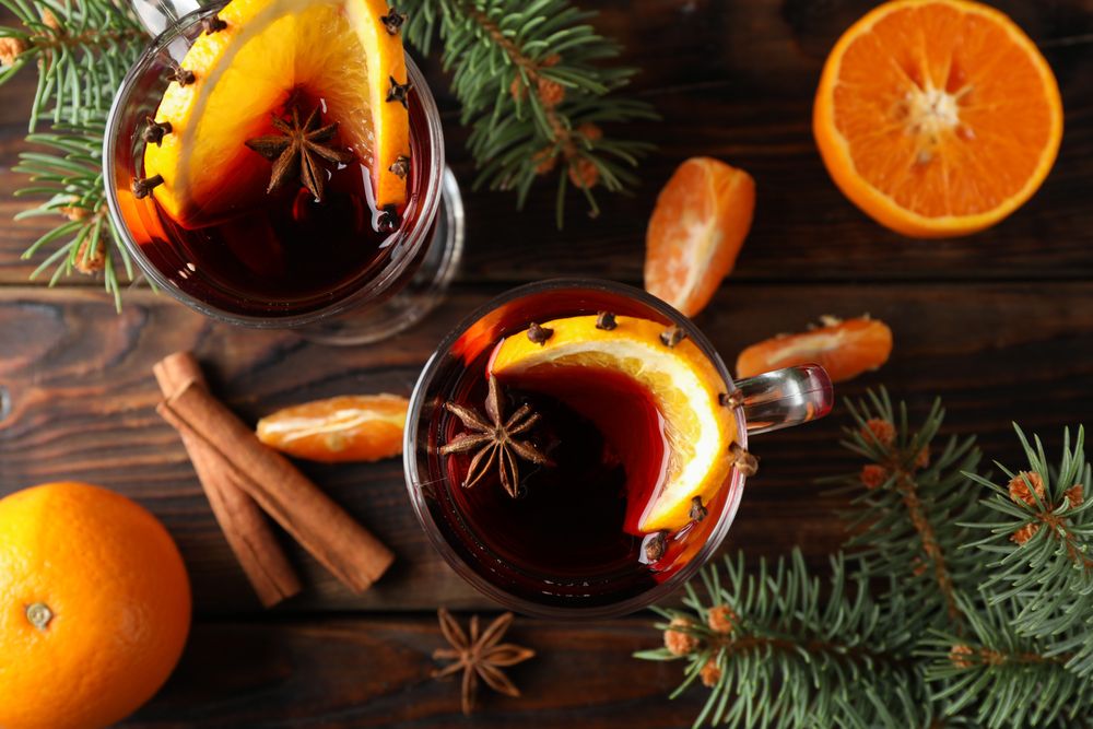 Glasses of tasty mulled wine with orange on wooden background, top view