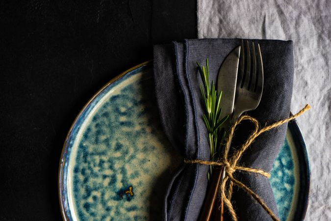 Christmas table setting of blue plate with rosemary sprig