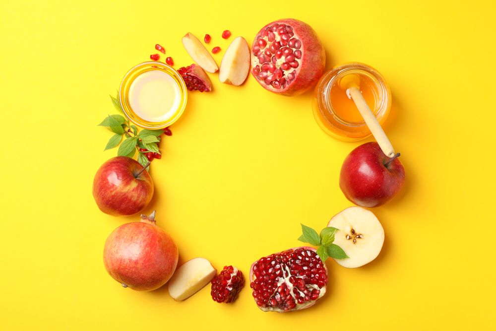 Wreath of apples, pomegranate, honey on yellow background