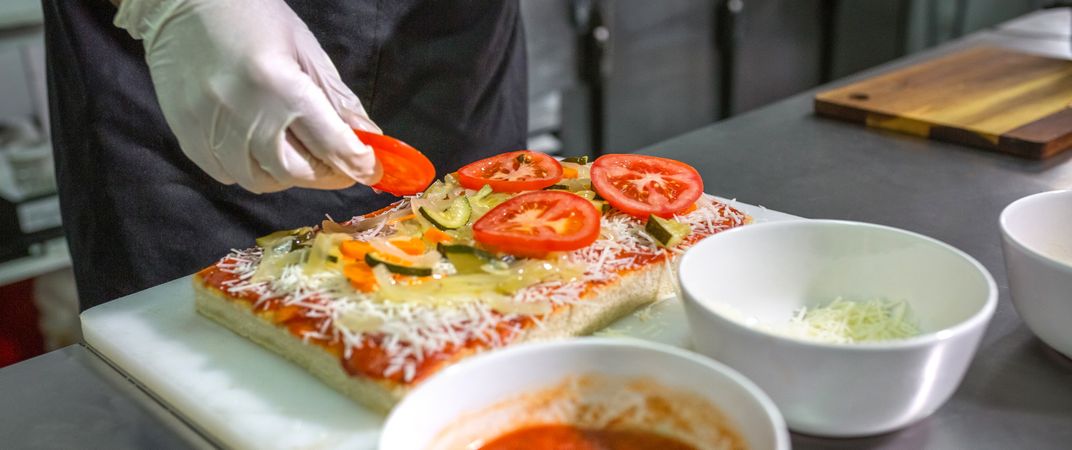 Banner of anonymous male preparing vegetarian pizza with healthy ingredients in a restaurant kitchen