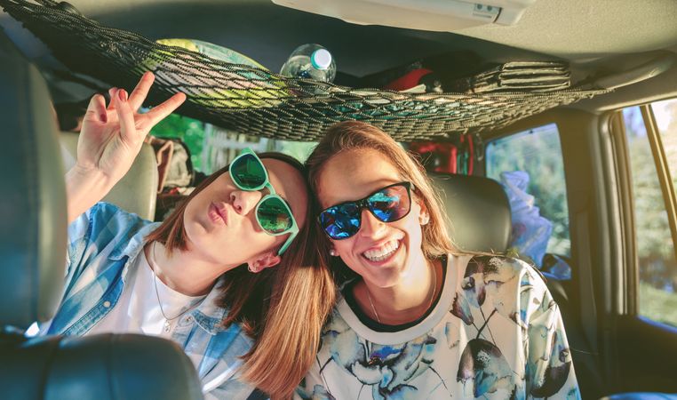 Happy women in sunglasses laughing and having fun inside of car