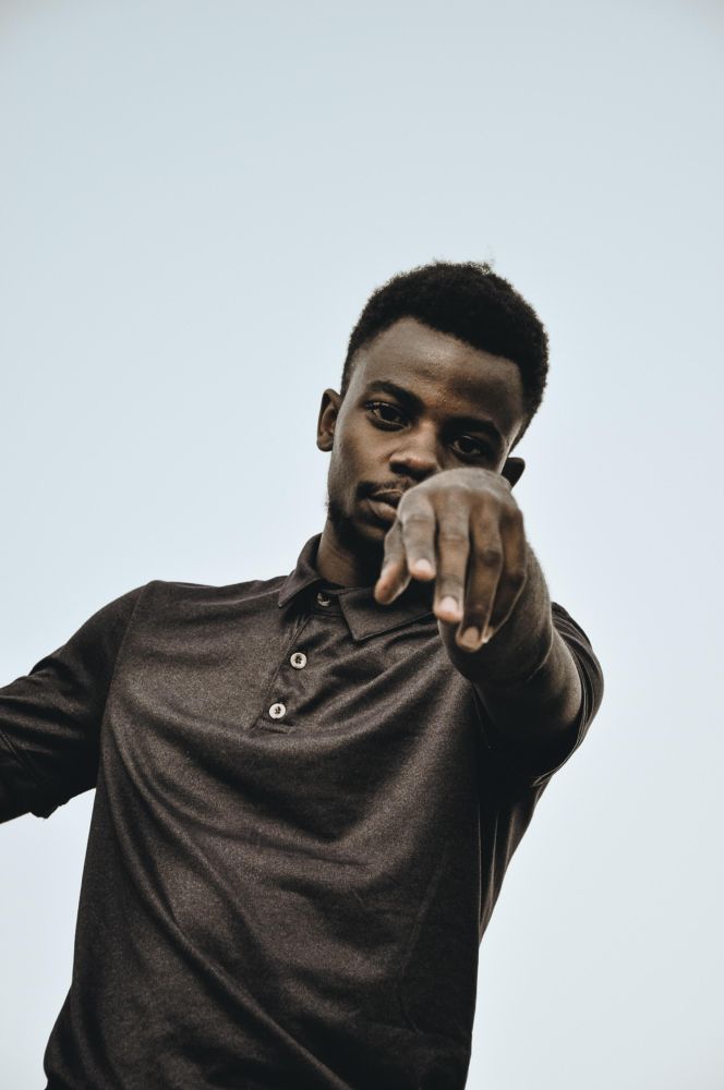 Man wearing dark polo shirt standing under clear sky