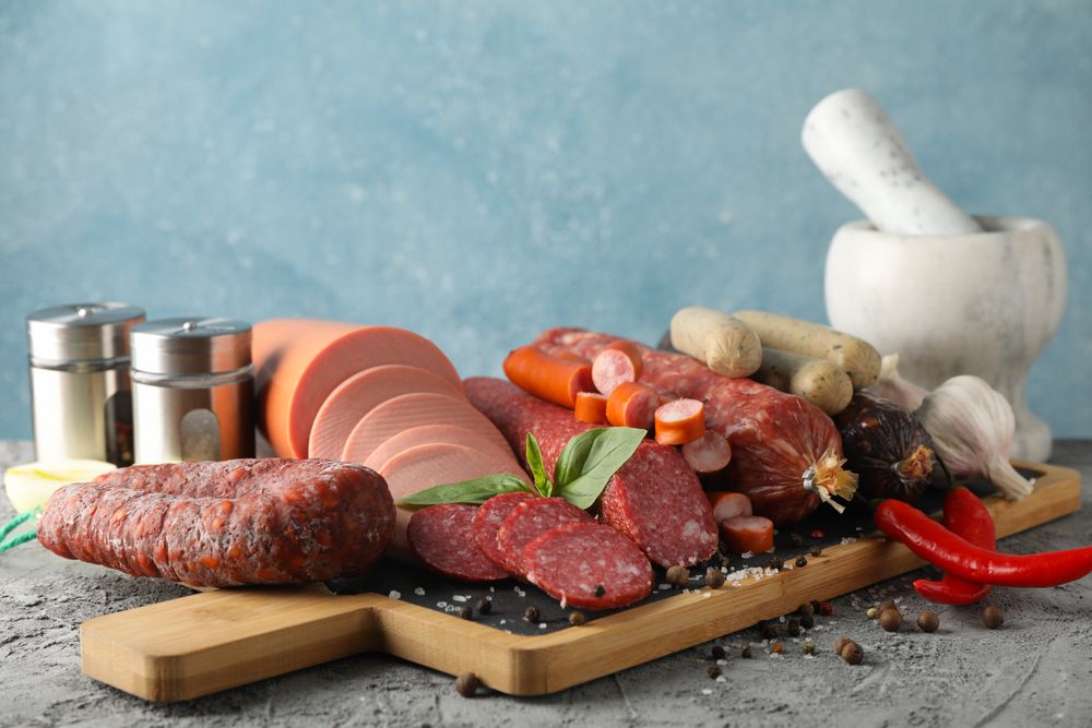 Board of cured meat variety, with salt and pepper, in blue kitchen